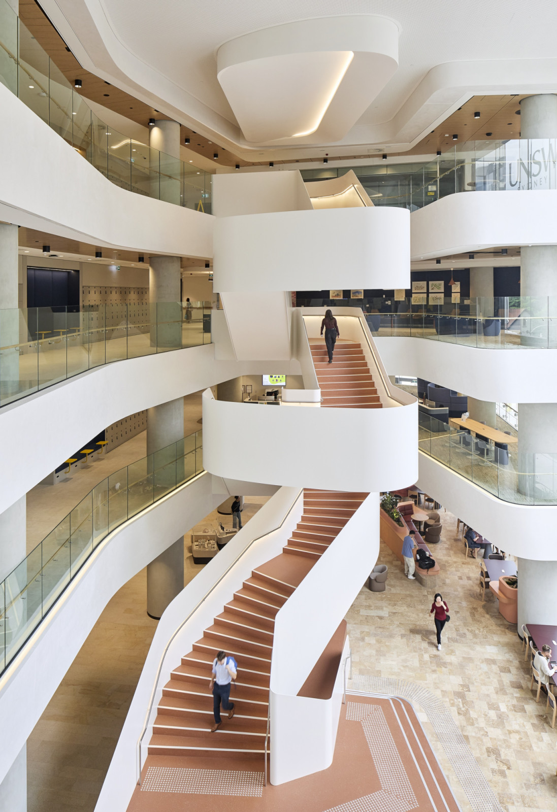 A terracotta staircase spirals through the atrium, connecting floors via sculptural white landings (Photo: Hufton + Crow)