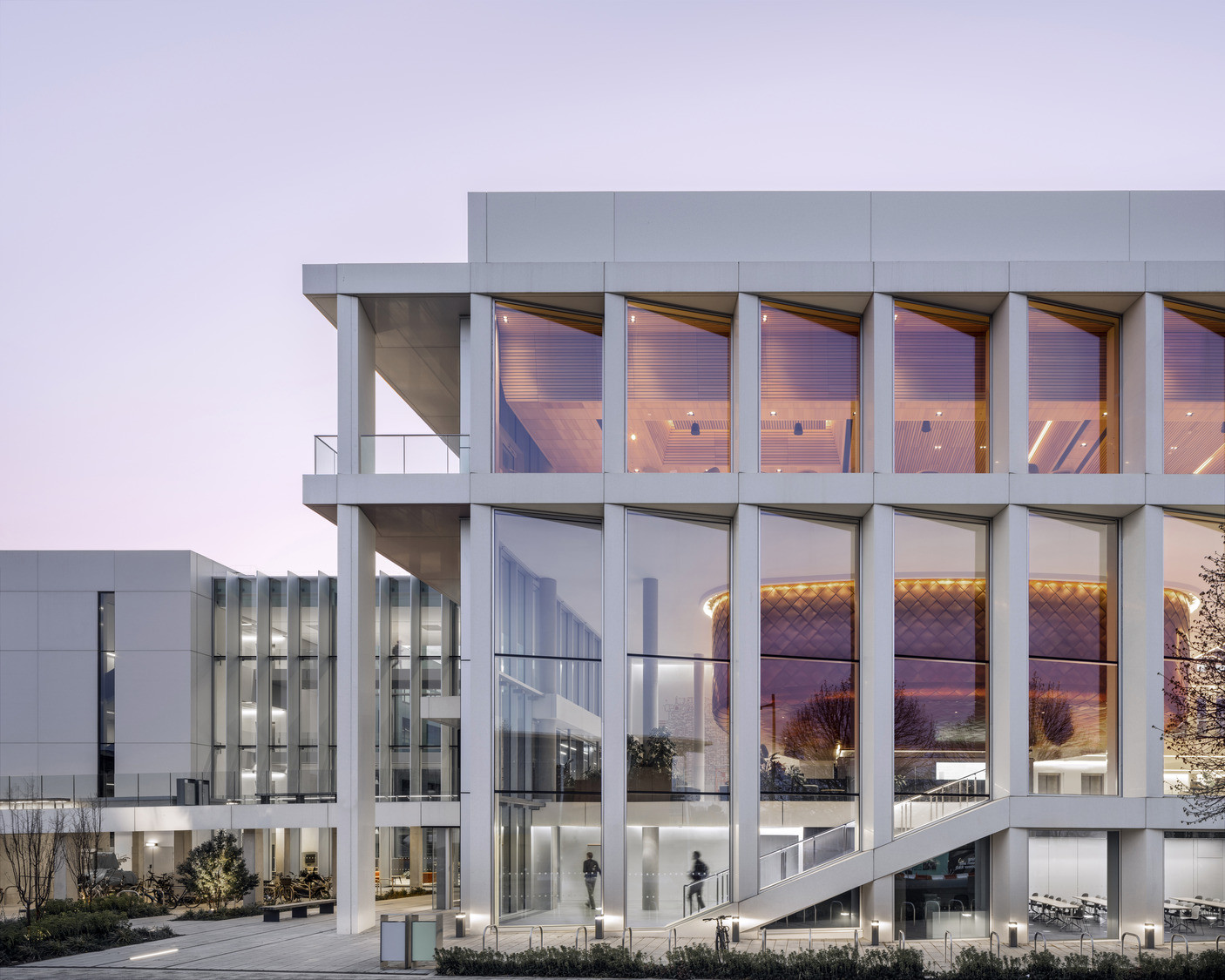 Glazed upper floors reveal a hammered copper volume within, its diamond pattern lit from inside at dusk (Photo: Kilian O’Sullivan)