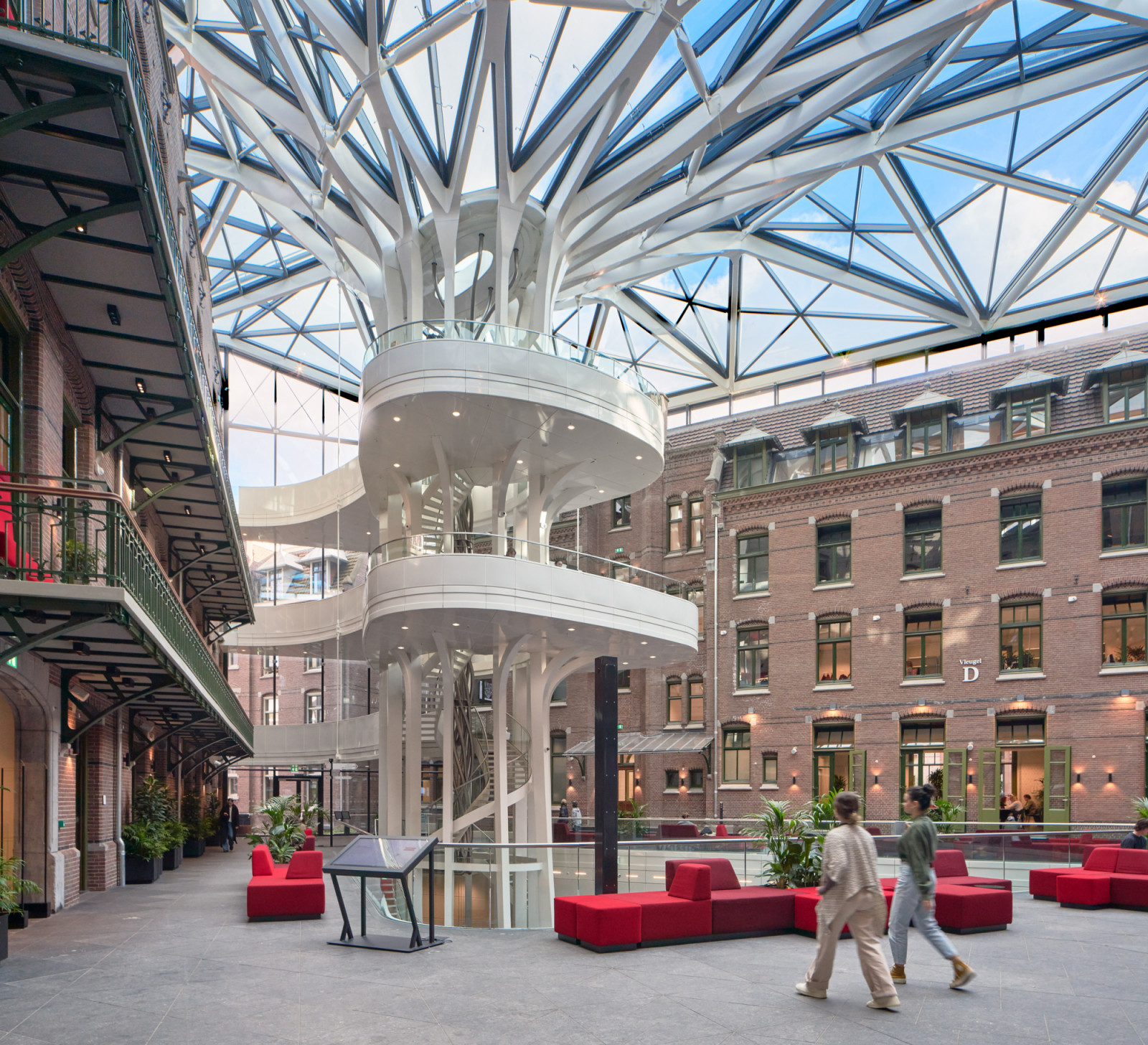 The sculptural “Tree of Wisdom” staircase branches upward through the atrium, its white balustrades curving around a central spiral stair (Photo: Ronald Tilleman)