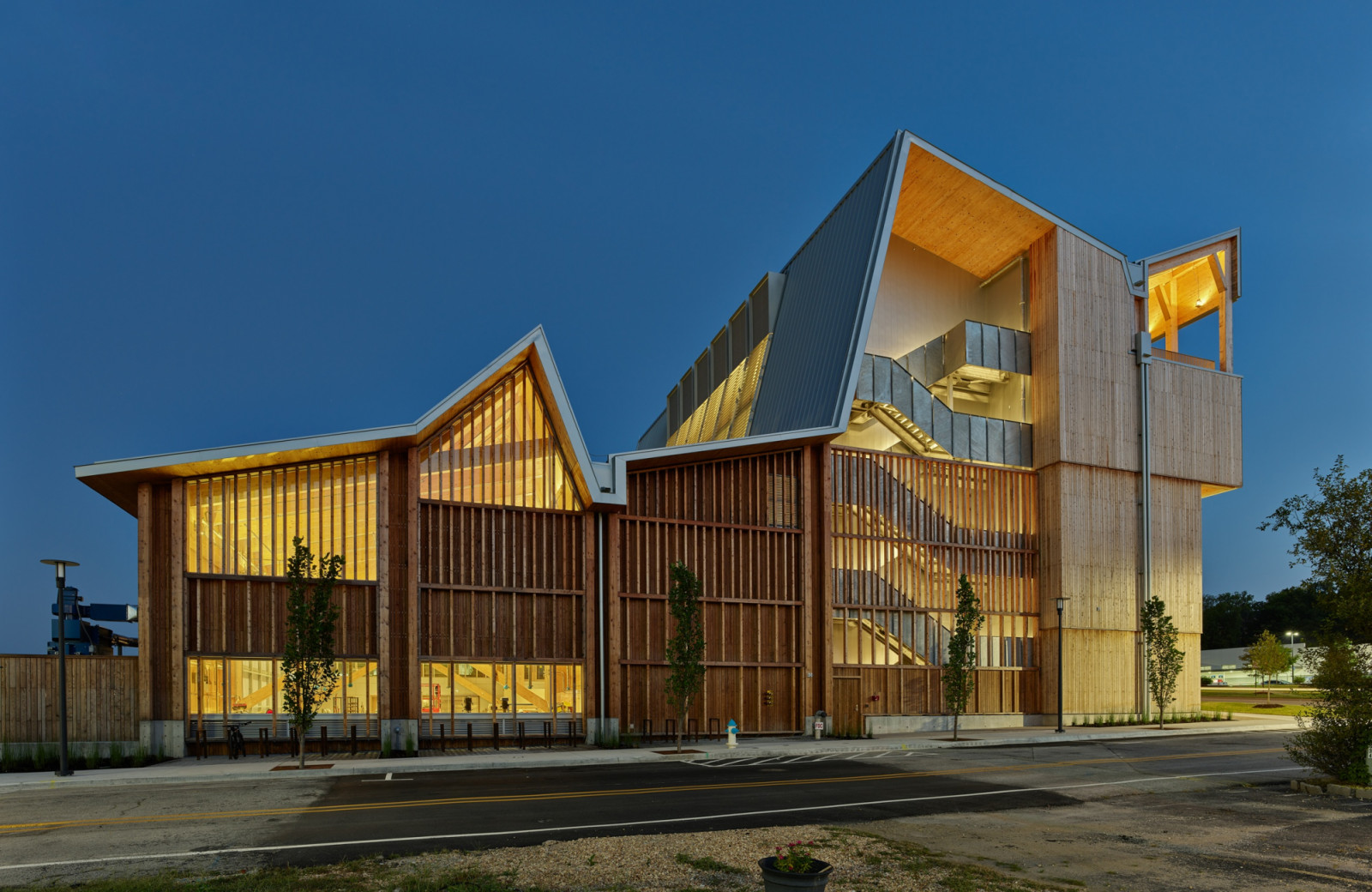 At dusk, the workshop’s illuminated interior glows through vertical timber screens along the building’s lower storeys (Photo: Timothy Hursley)