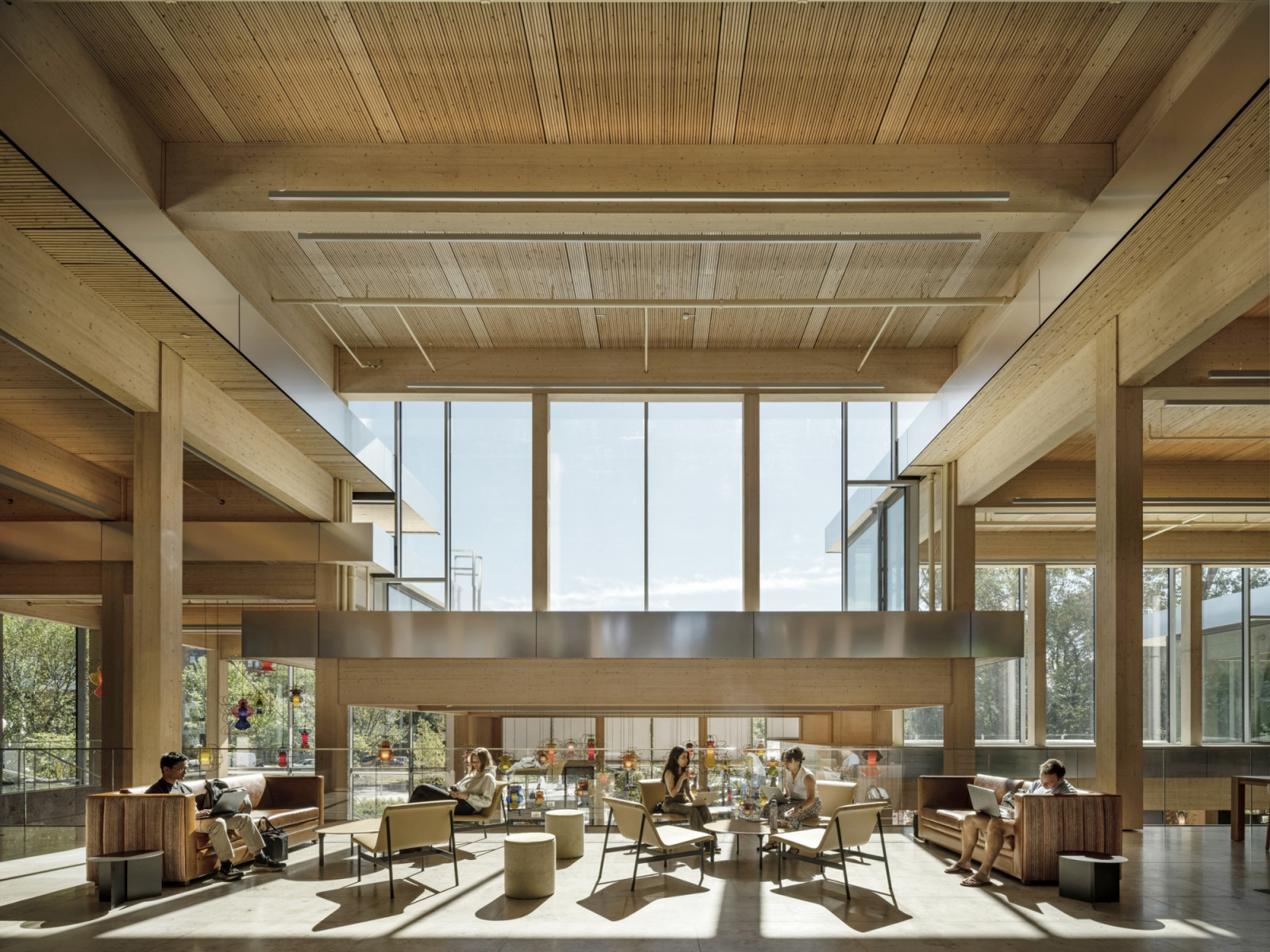 Timber columns and beams frame a sunlit lounge furnished with leather sofas and low tables, where students work on laptops (Photo: Laurian Ghinitoiu)