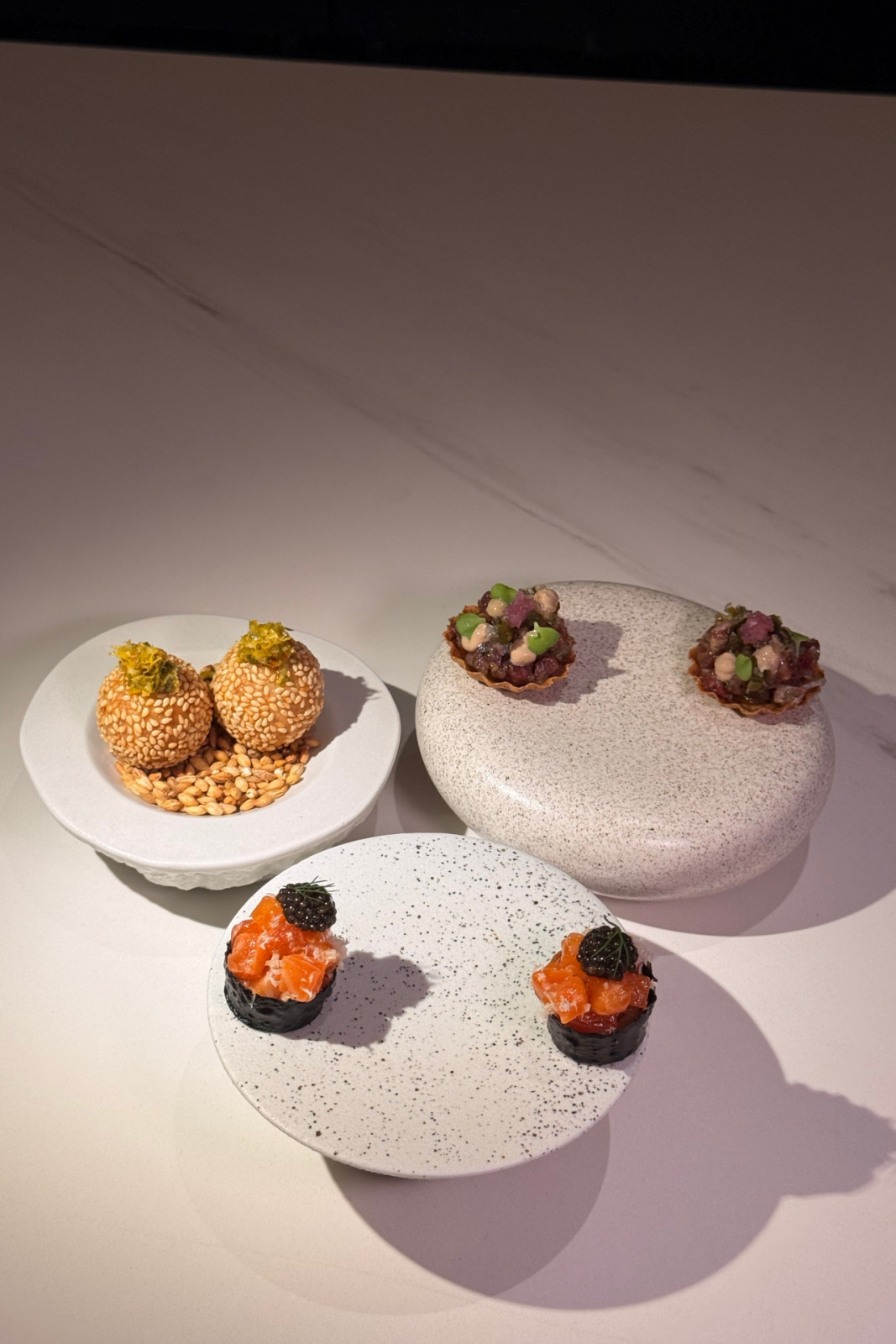 The snacks from Helm by Josh Boutwood's Single Ingredient menu: Squid ink croustade with trout, mustard leaf, pickled cucumber, caviar, fresh horseradish; savoury buchi with toasted sesame, lobster and prawn bisque, lime kosho; a rye tart with Wagyu tartare, egg yolk gel, black garlic aspic, shiso leaf.