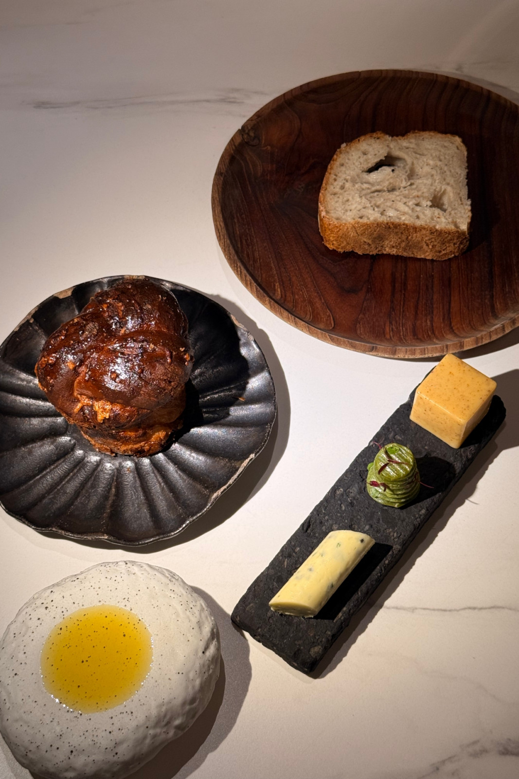 Sourdough and laminated brioche with aged Gouda, sharp cheddar, and a trio of butter (caramelised butter, pork chicharon, confit garlic, thyme, caviar butter) plus Tuscan olive oil from Helm by Josh Boutwood's Single Ingredient menu
