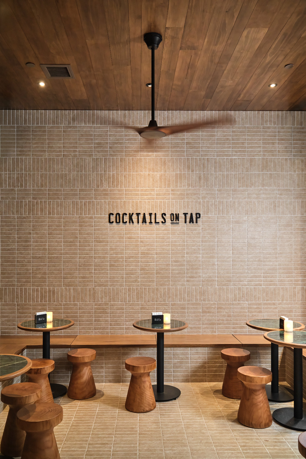Experience 'Cocktails on Tap' in a newly designed space, featuring bespoke wooden stools and contemporary tiled walls.
