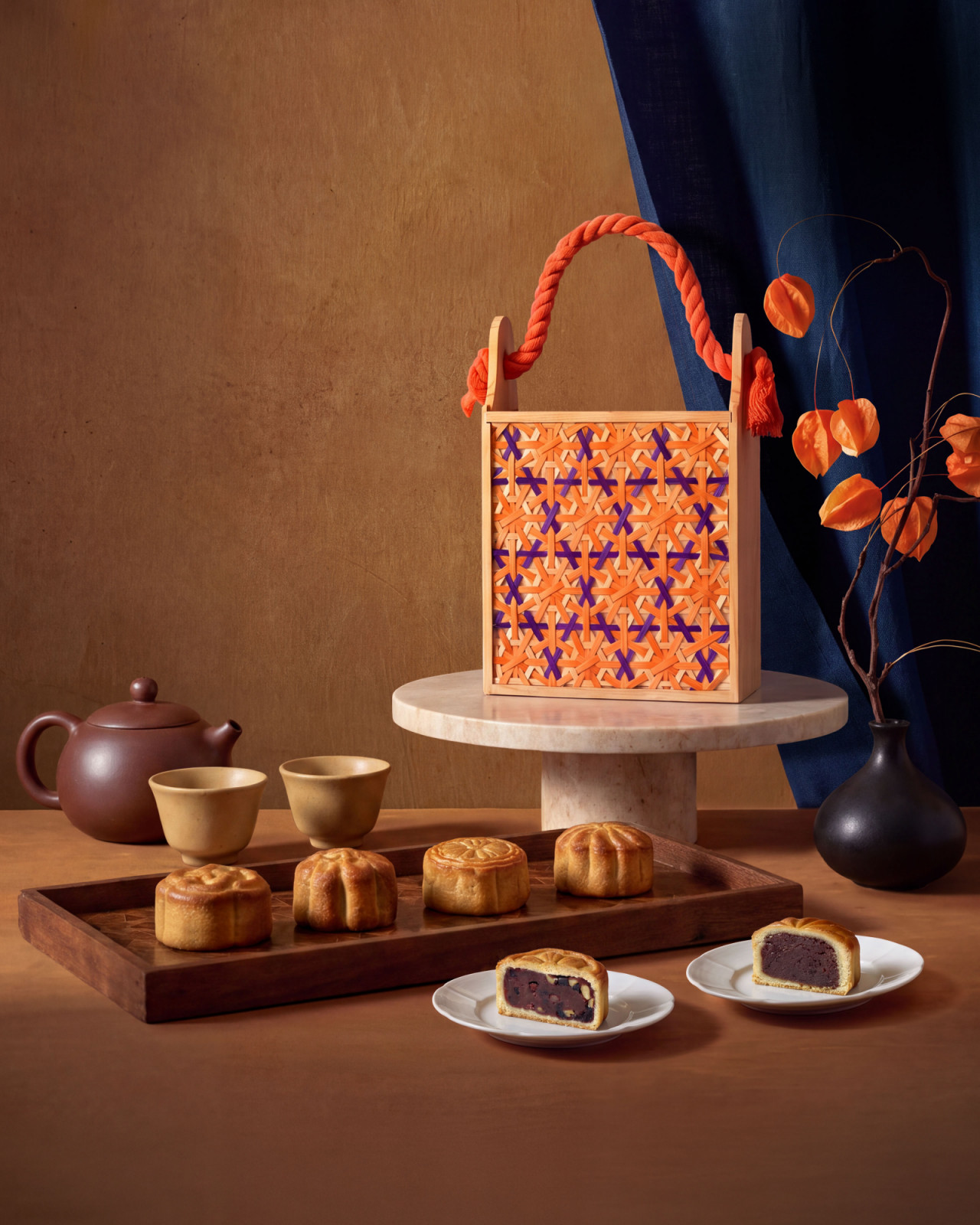 Mooncakes with varied fillings, served alongside a traditional tea set and presented in a handcrafted gift box.