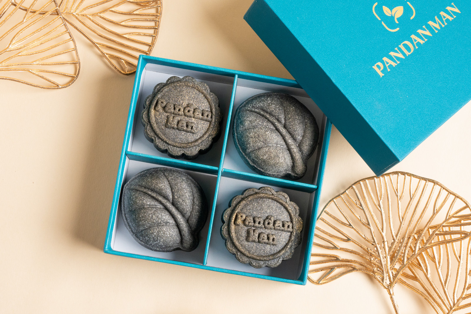 Pandan Man offers a box of four artisanal mooncakes, featuring the brand's logo and intricate leaf designs.