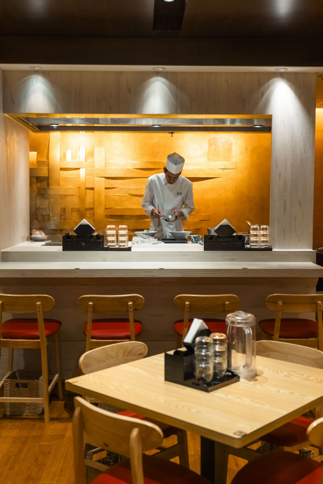 A chef prepares dishes behind the counter, a central feature for diners at this restaurant.