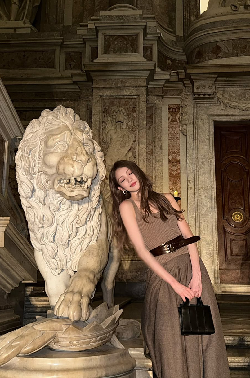 Actress Lee Sung-kyung showcases her monochromatic style next to a classical lion sculpture.