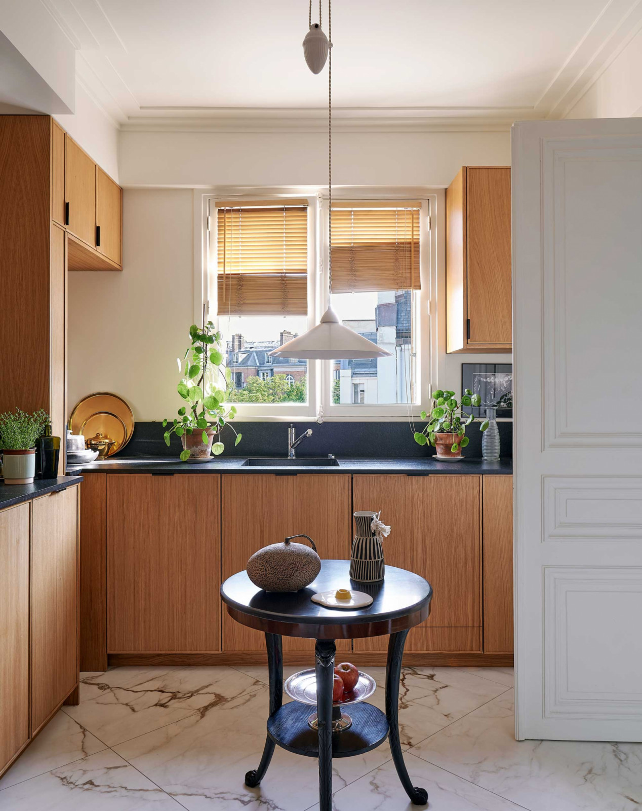 The kitchen features a black Empire-style pedestal table displaying ceramics