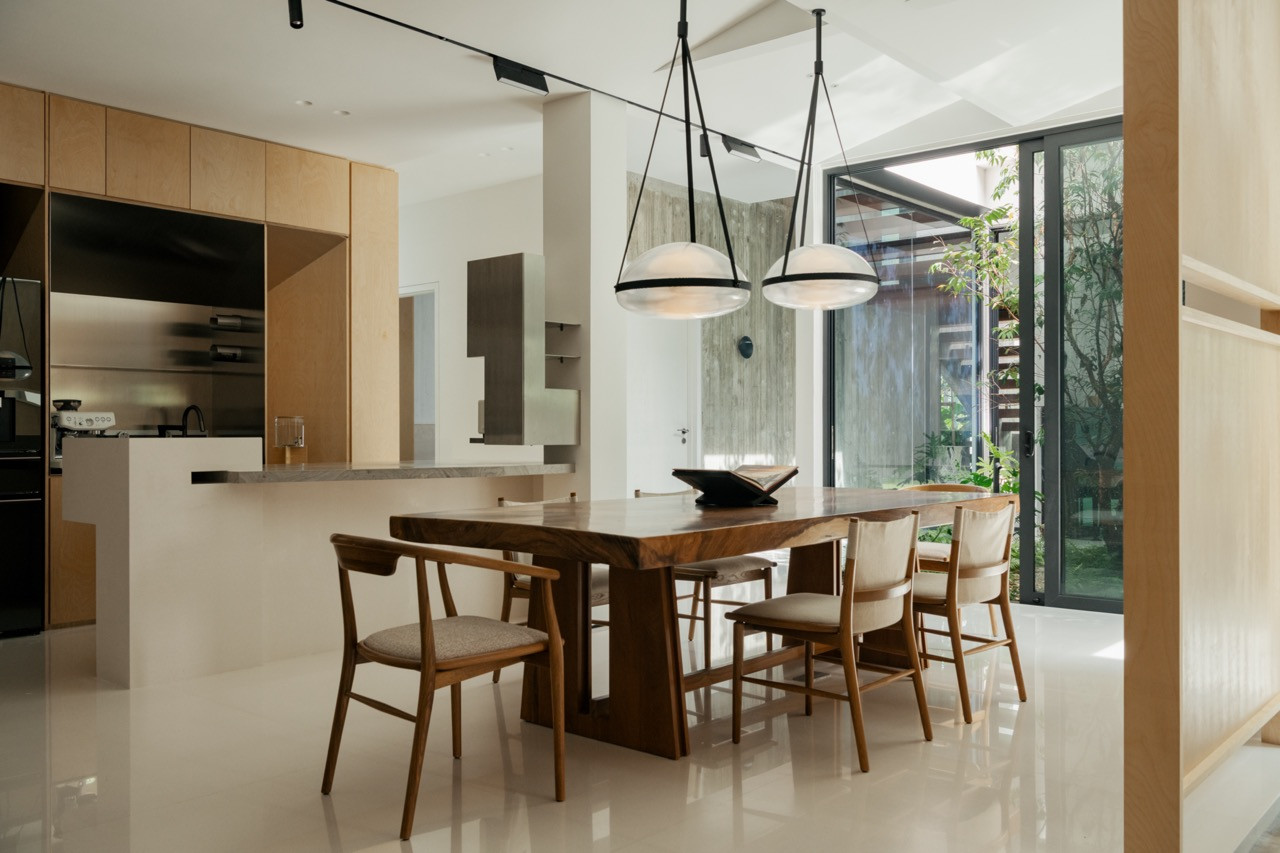 The dining area viewed from the open kitchen, with a marble breakfast bar and floor-to-ceiling glazing onto the garden