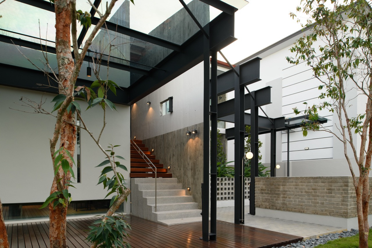 The same steel-framed canopy is seen from the garden, with young trees planted along the deck’s edge