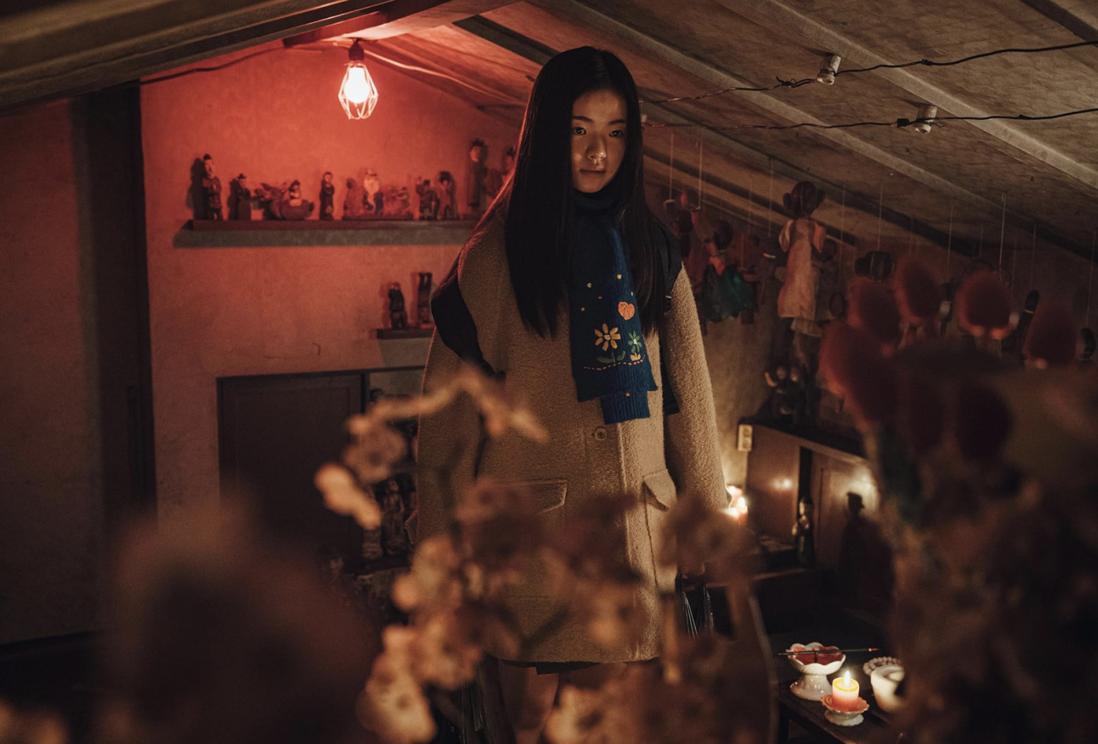 A young woman with a focused gaze in a richly detailed, red-lit interior, showcasing the diverse storytelling of K-dramas.