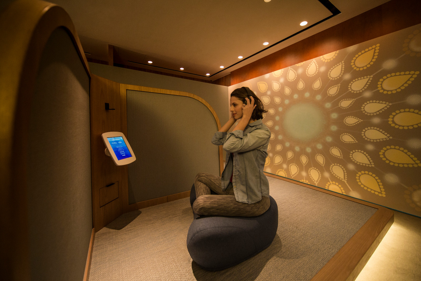A traveler finds calm in a dedicated wellness pod, offering a personalized audio experience at an Asian airport.