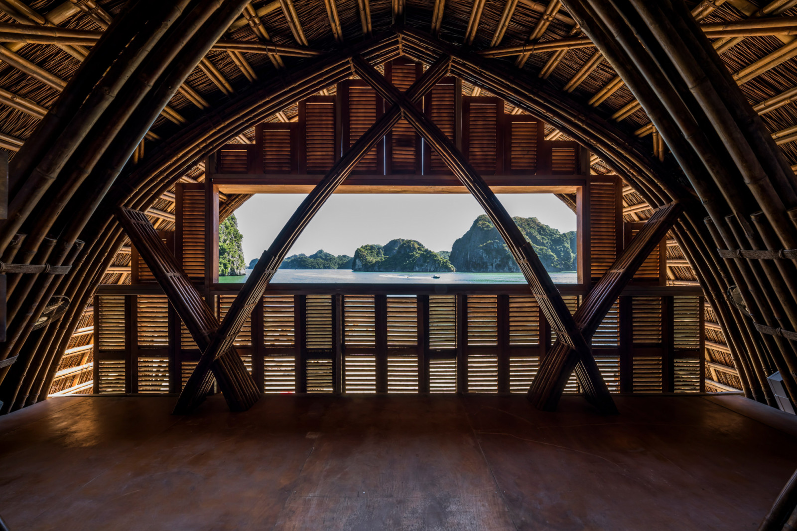 Inside one of Castaway Island’s bamboo-framed structures, shuttered wooden screens and crossed bamboo braces frame a view out to the bay’s islands