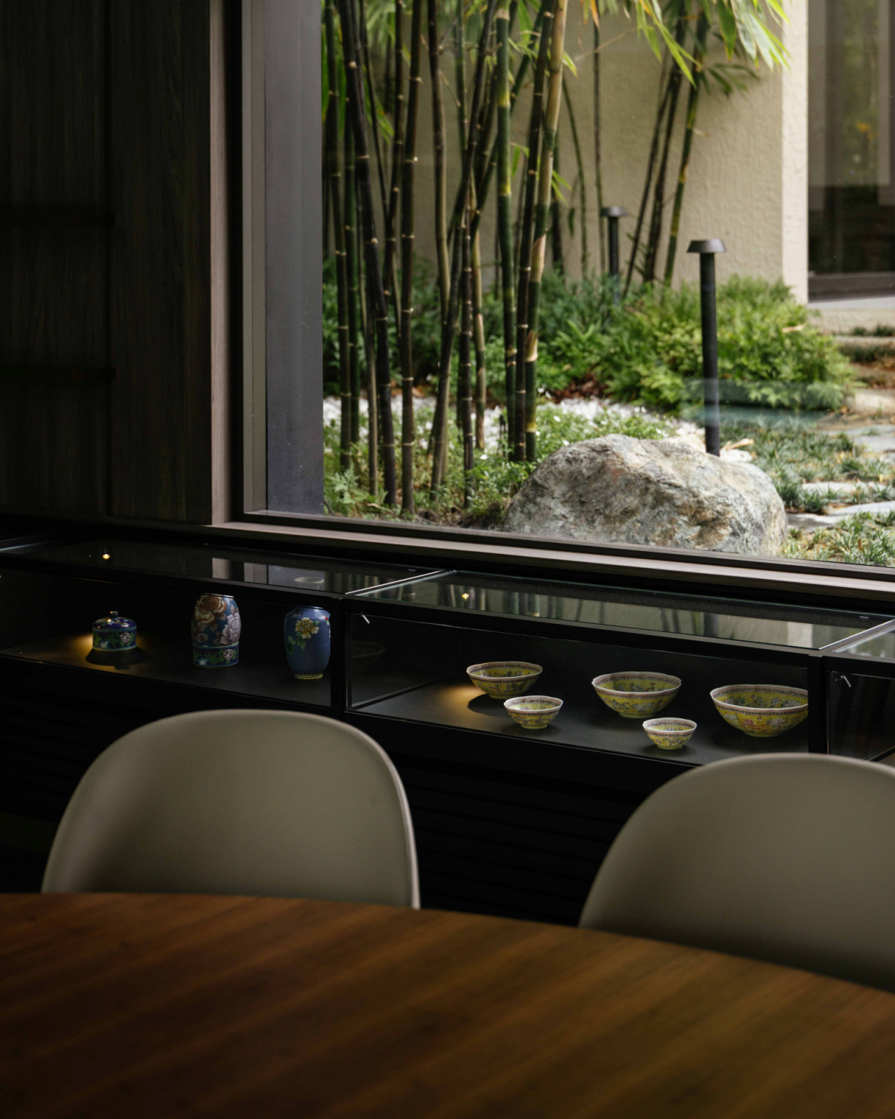 The dining area display cabinet frames the Timor black bamboo and a sculptural boulder, blurring collection and landscape