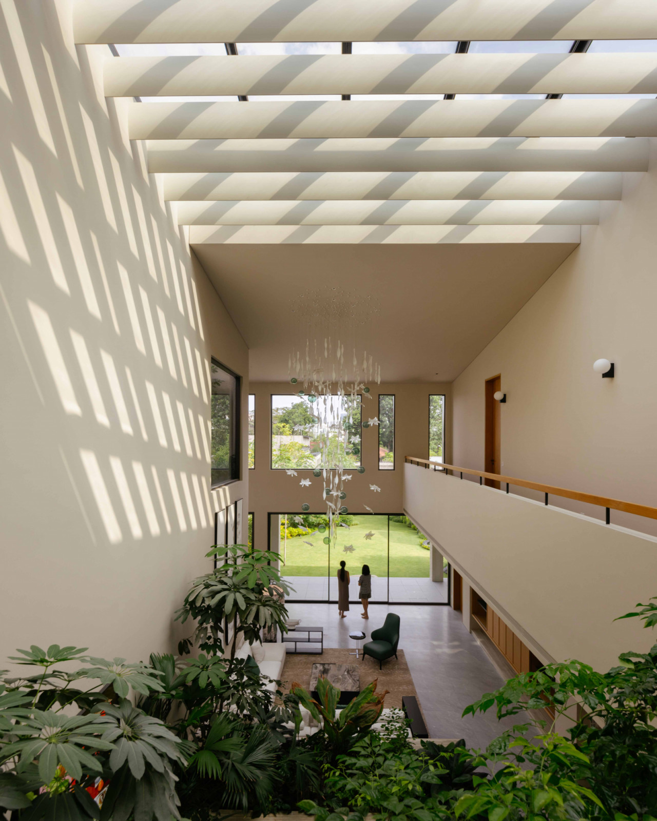 In the double height family lounge, a Sipek & Spalek chandelier of floating crystal leaves guides the eye along the linear walkway towards the garden beyond