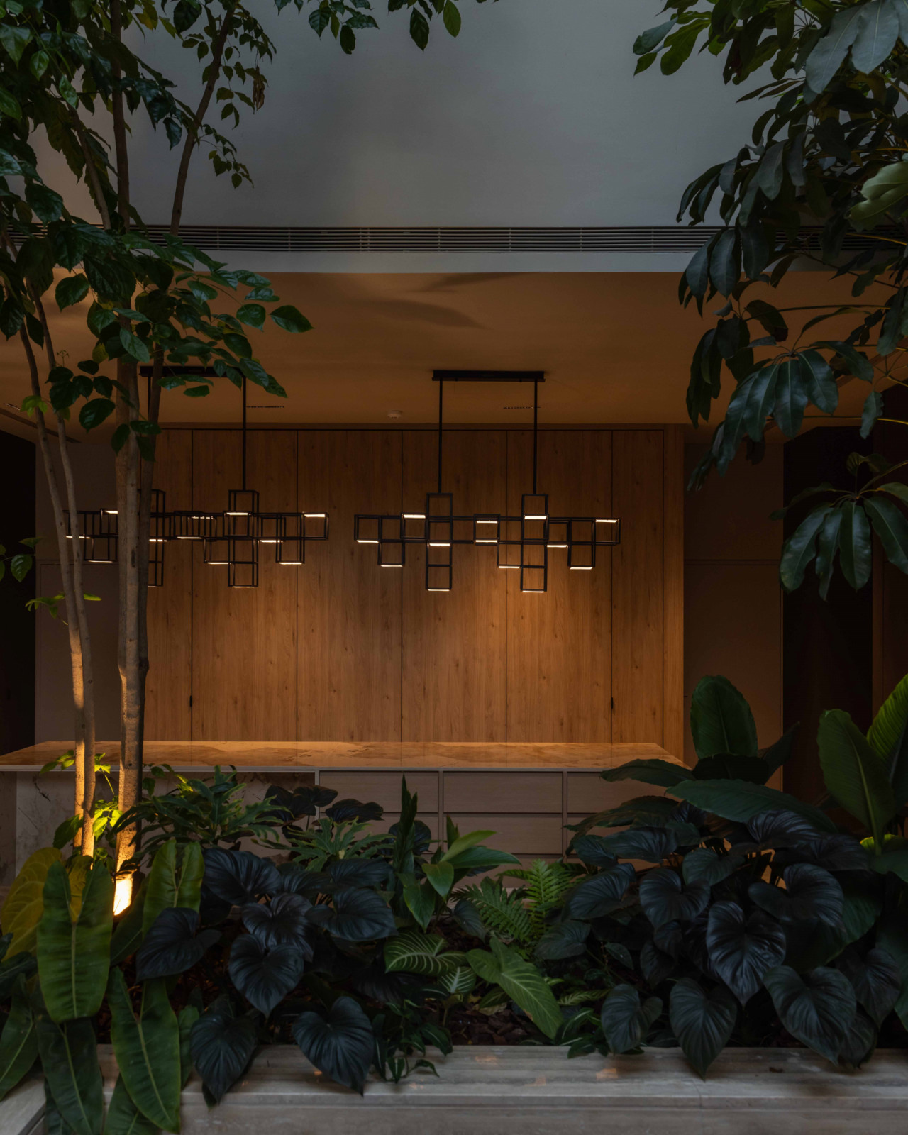 At dusk, the dining pavilion glows through a veil of garden foliage