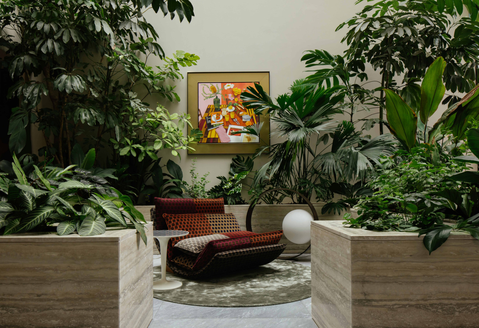 Dense tropical foliage envelops a seating nook beneath a vivid painting in the master pavilion’s indoor garden