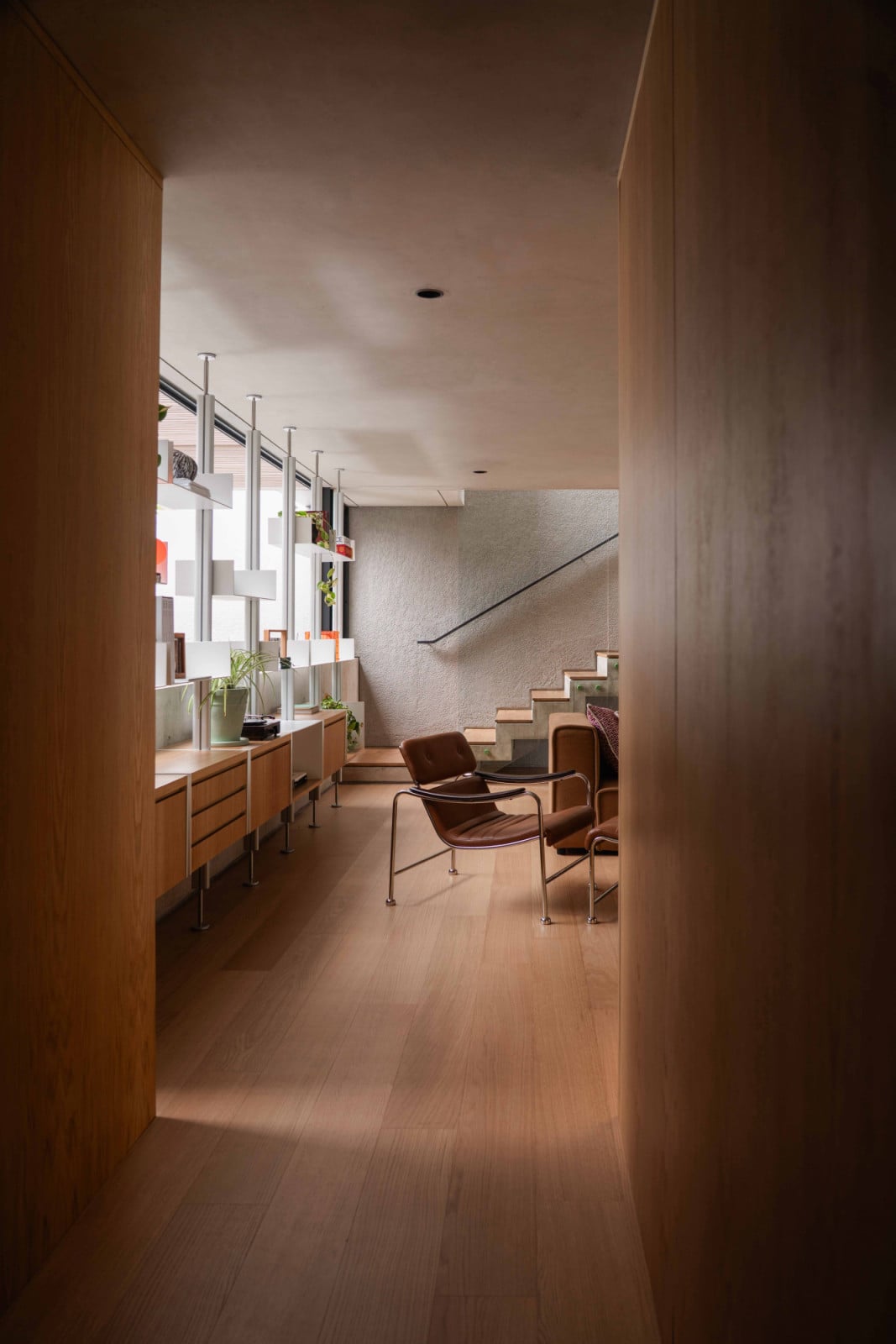 View of the Bandung home’s mezzanine lounge and library from a timber-clad corridor