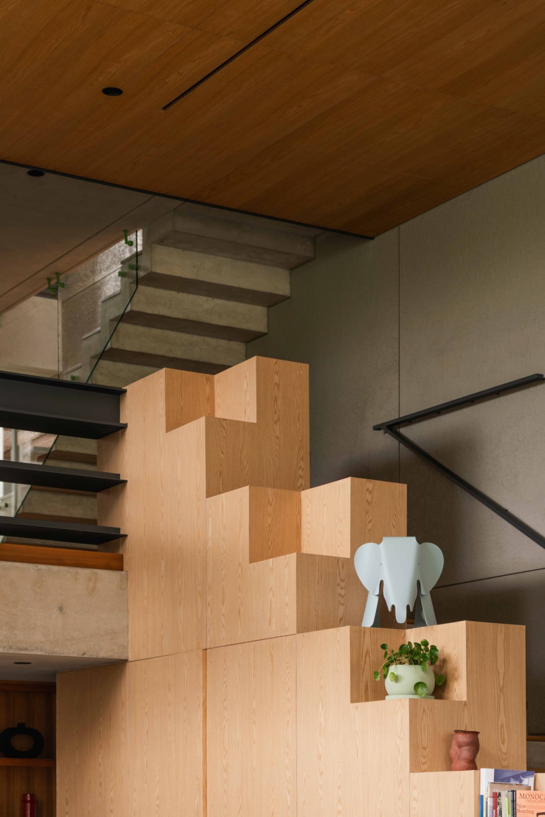 Display steps beside the stair hold books, like the Vitra Eames Elephant, plants and small objects within easy reach