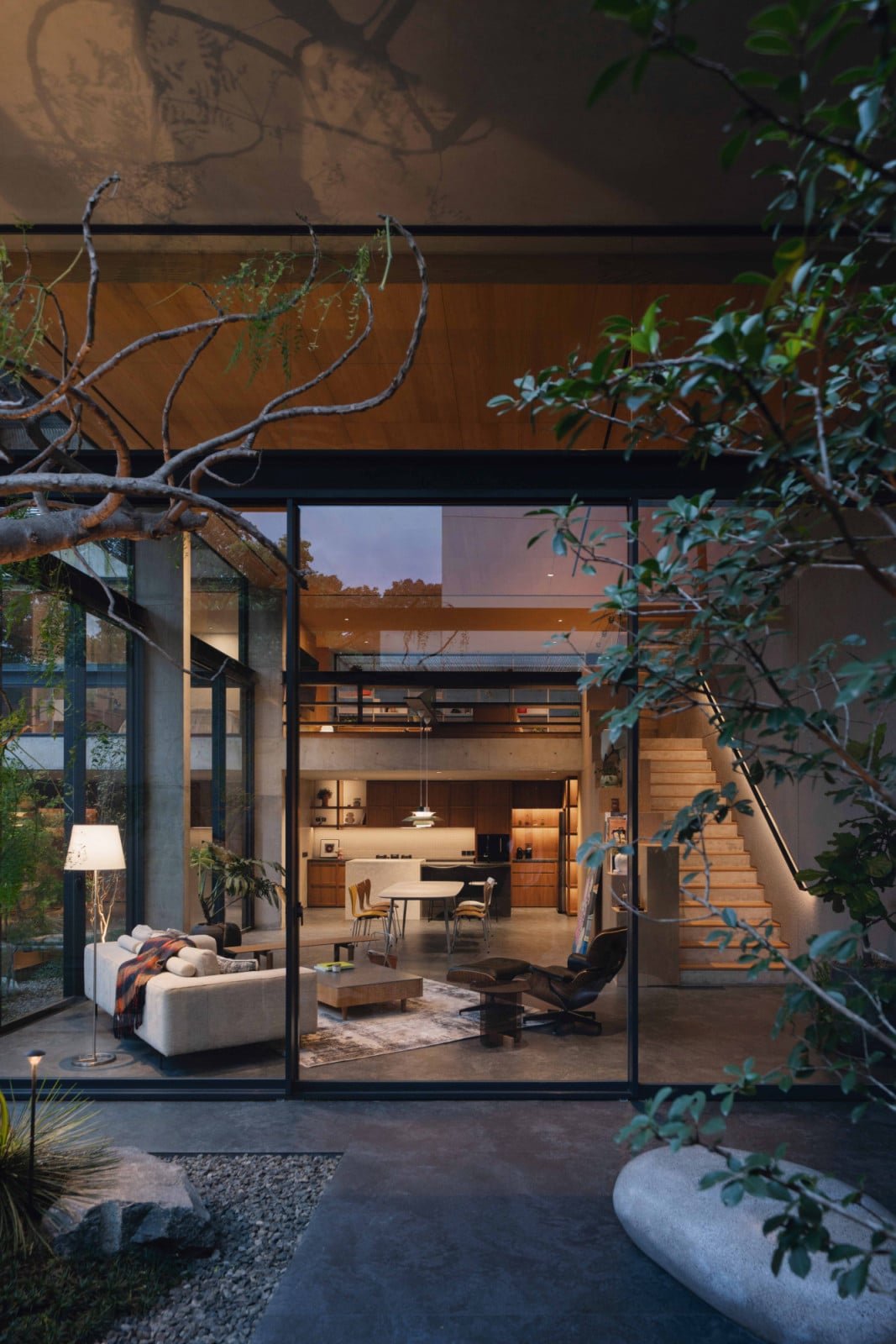 Seen from the garden at dusk, the Bandung home’s living room glows as if it were simply another part of the landscape