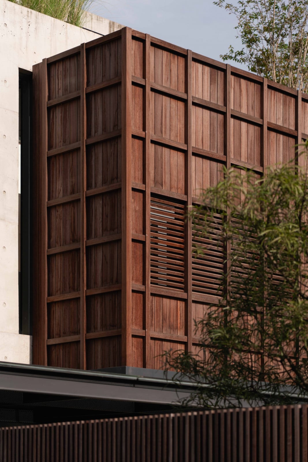 A section of the timber facade pivots open, breaking its solidity with a sliver of natural ventilation