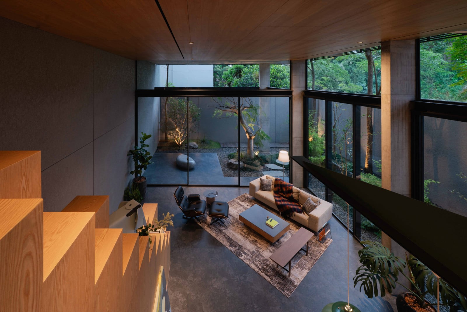 The double-height living space is furnished with iconic designer pieces such as the Herman Miller Eames lounger and Fritz Hansen Series 7 chairs, and opens out to the garden, its glazing calculated so the tree canopy stays in view even when one is seated