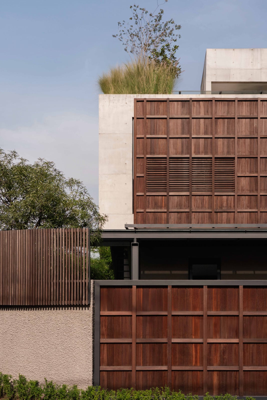 A rooftop garden crowns the timber-clad wing, softening Lift House's guarded street façade in Bandung