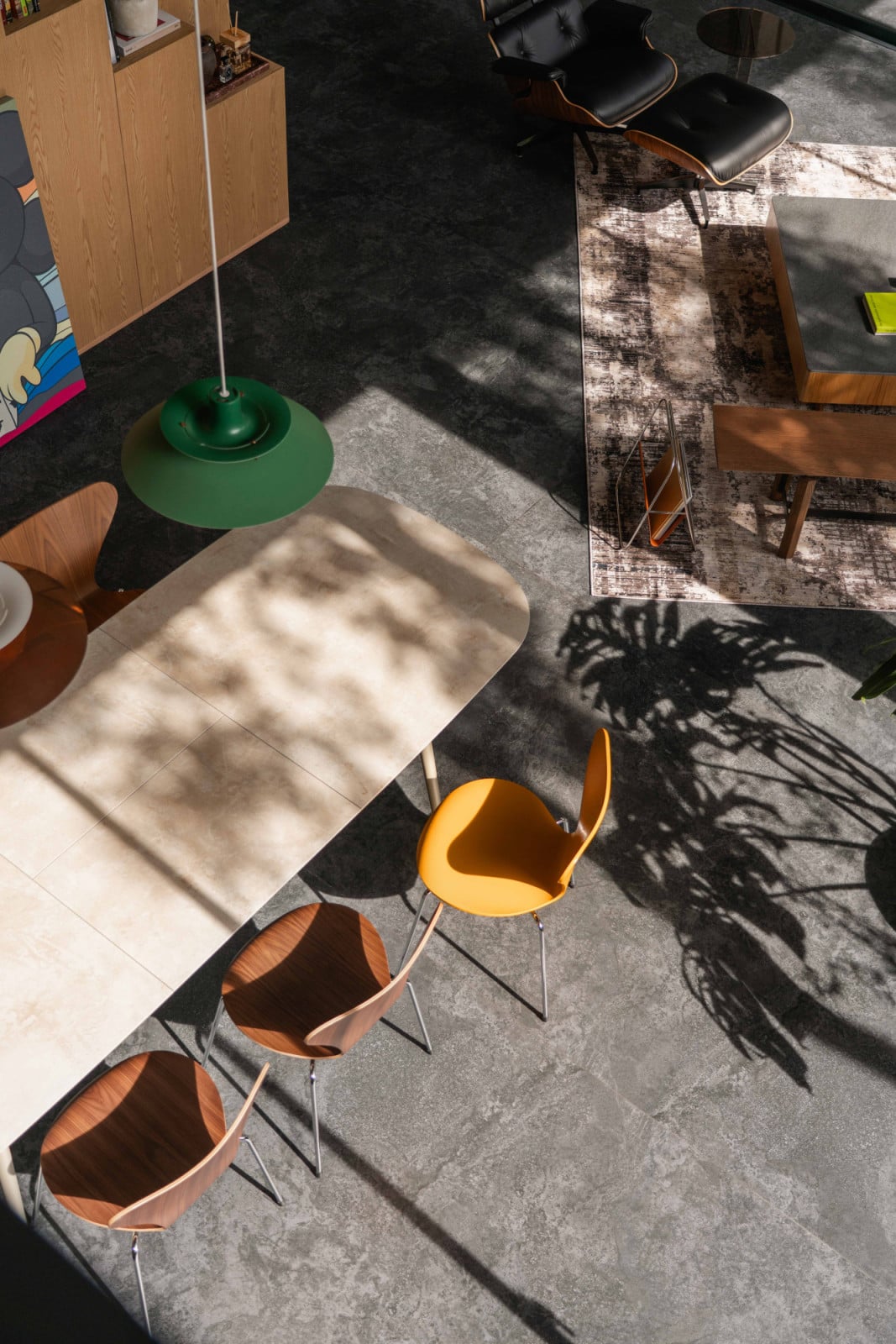 Seen from above, dappled light patterns the dining area furnished with Fritz Hansen chairs, beneath its green Louis Poulsen pendant