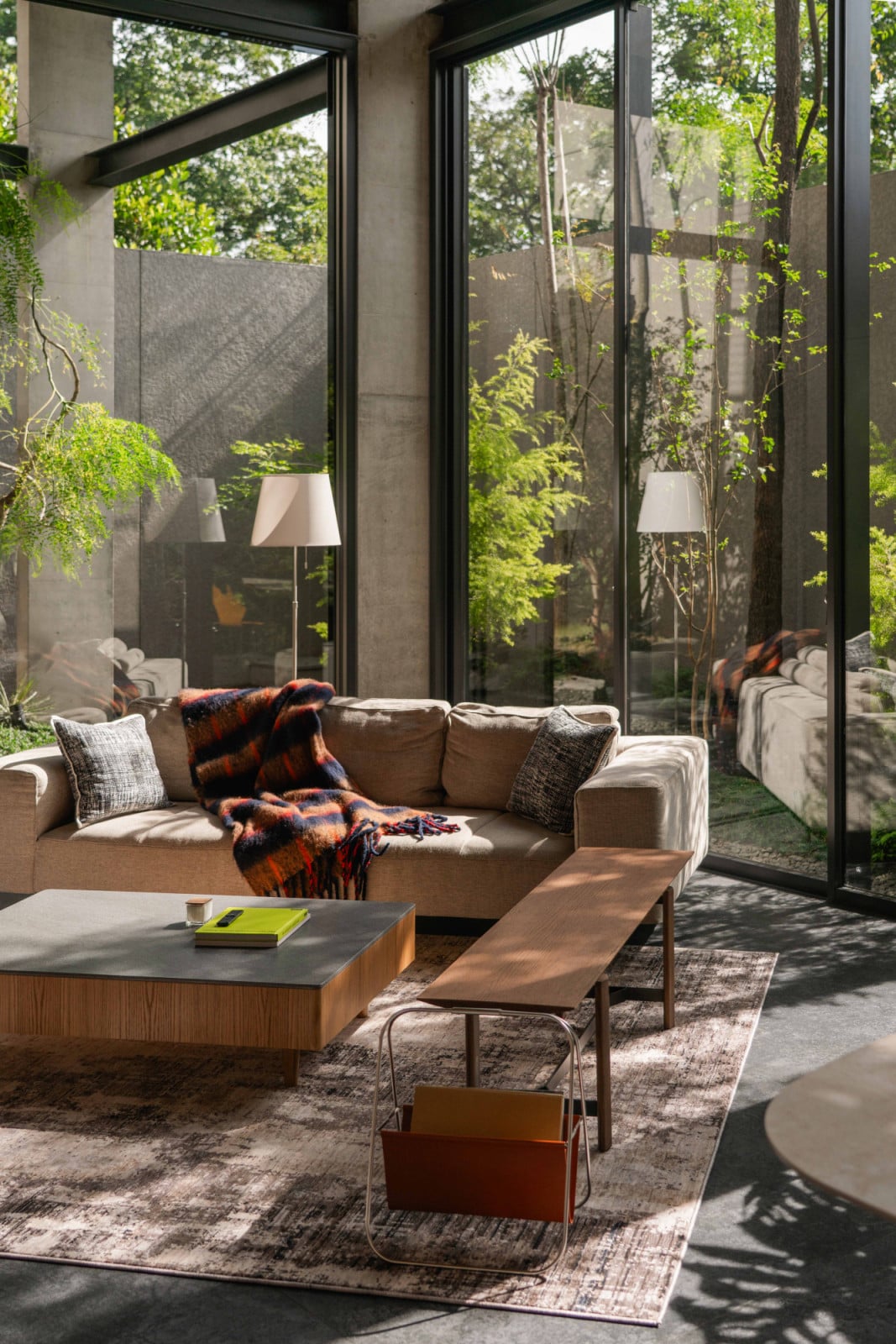 Layered glass reflections blur the living room and garden into one continuous space.