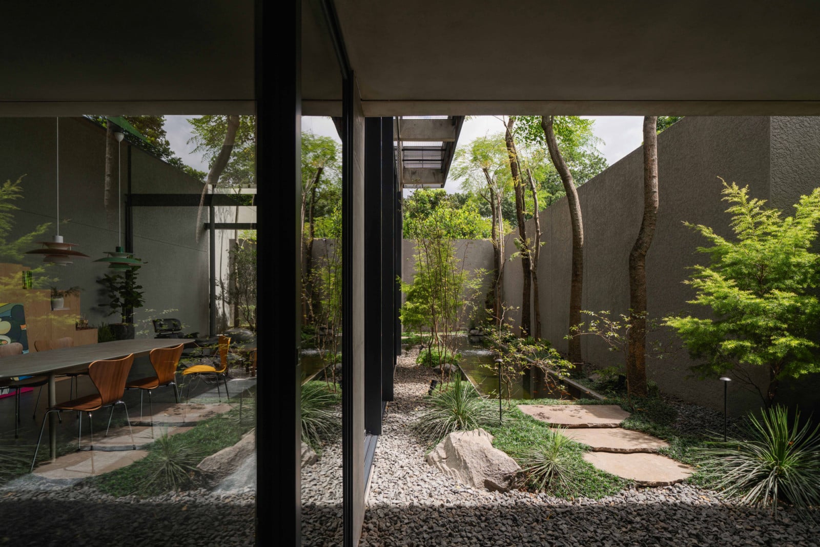 A narrow garden fills the space between the house and its boundary wall, giving the dining room a view of greenery even at its tightest edge