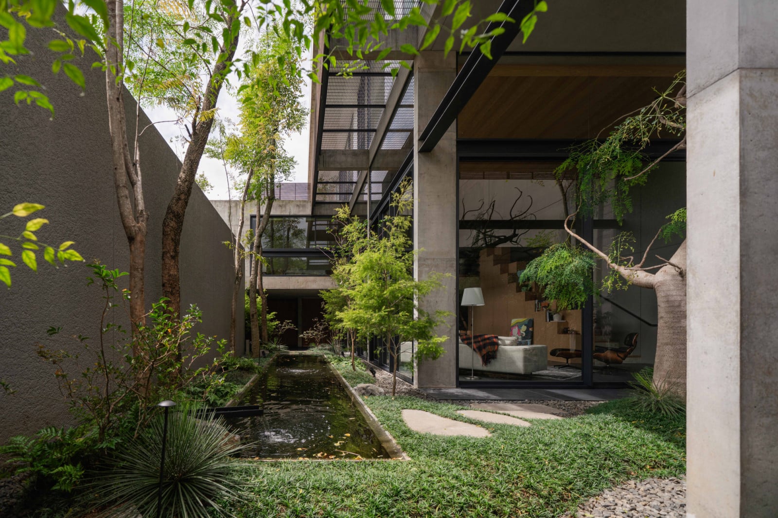 A slender koi pond traces the garden path alongside the living room's glass wall