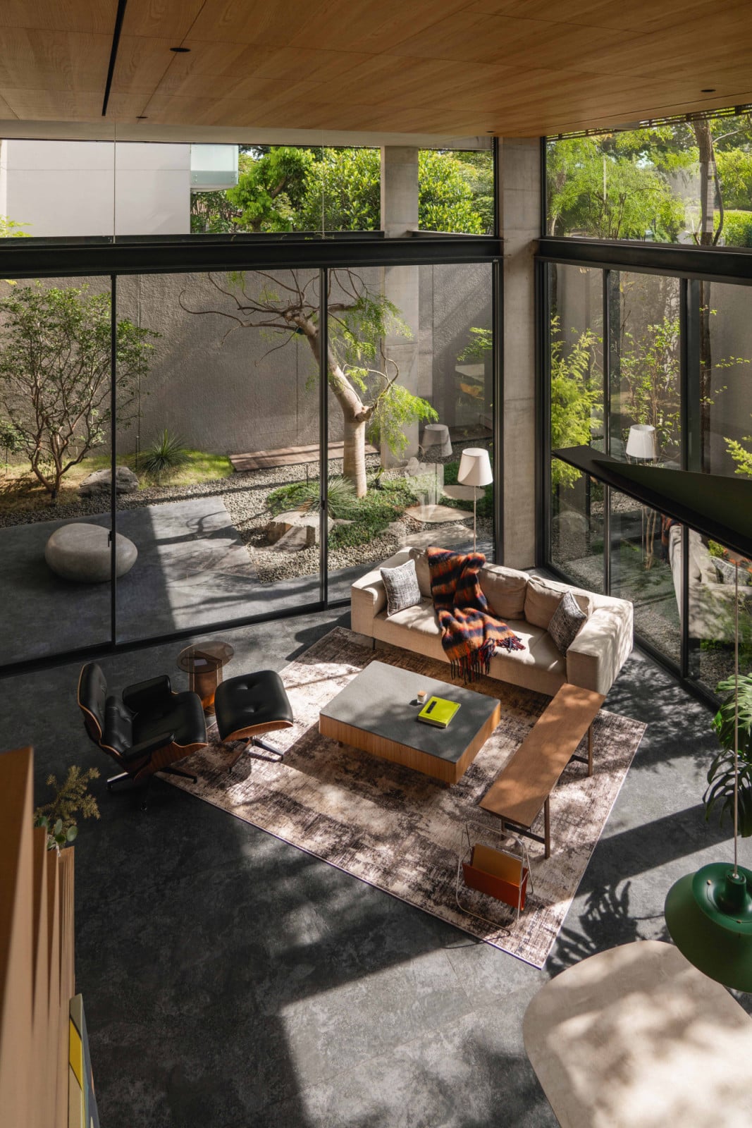 From the mezzanine, the Bandung home’s living room and garden below read as one uninterrupted volume