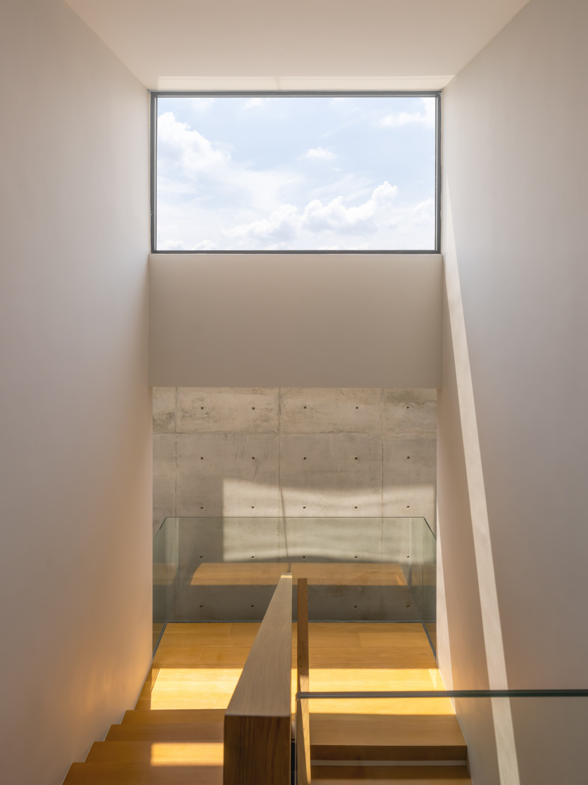 A skylight above the staircase draws daylight down past a poured concrete wall