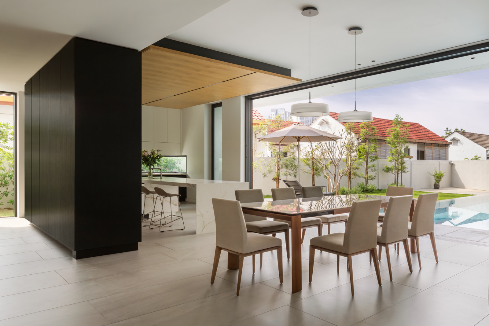 The dining and kitchen areas open onto the pool and garden through a wide glazed opening