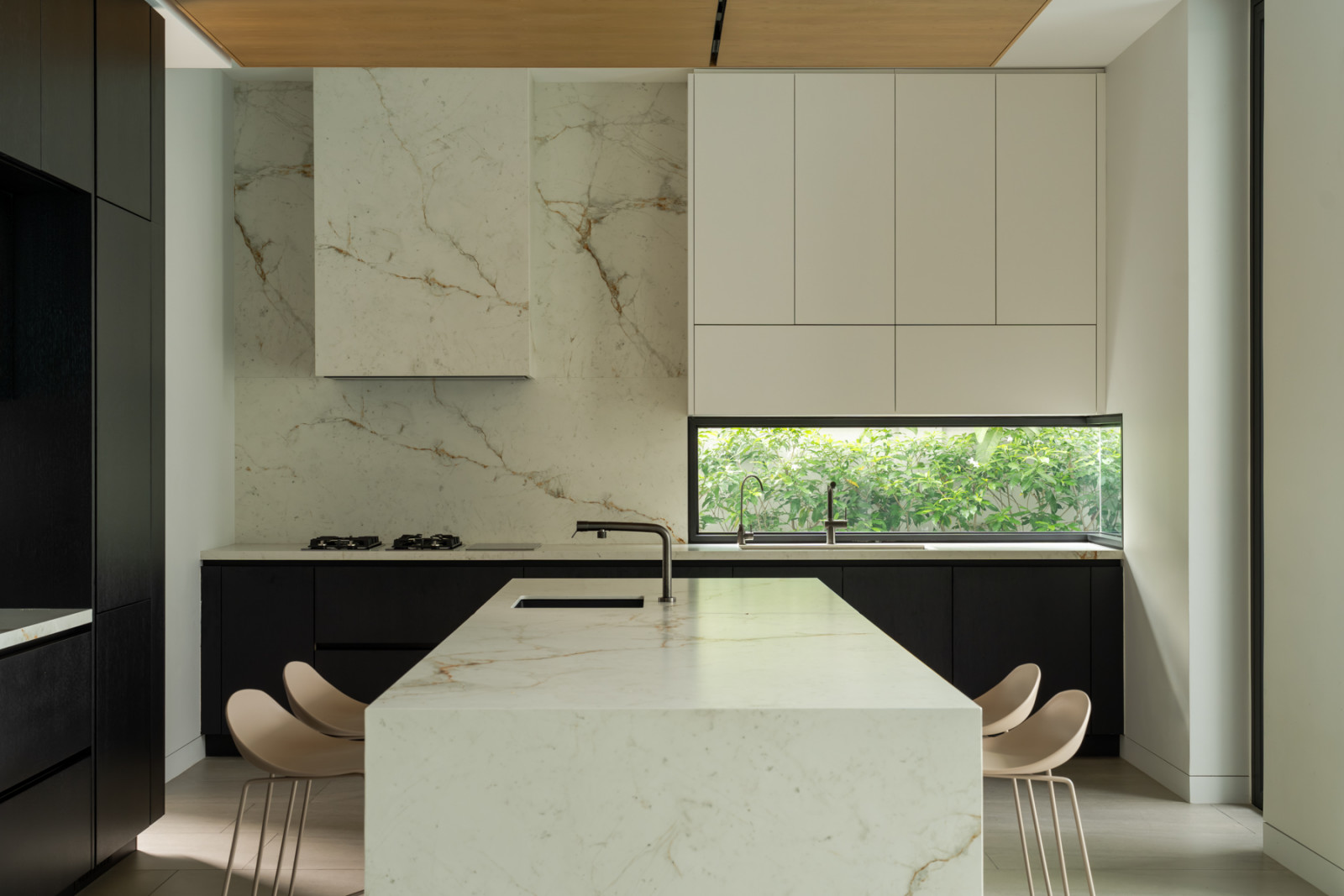 Stone slabs from Neolith clad the kitchen’s backsplash and island, with the same corner window bringing in a view of the garden
