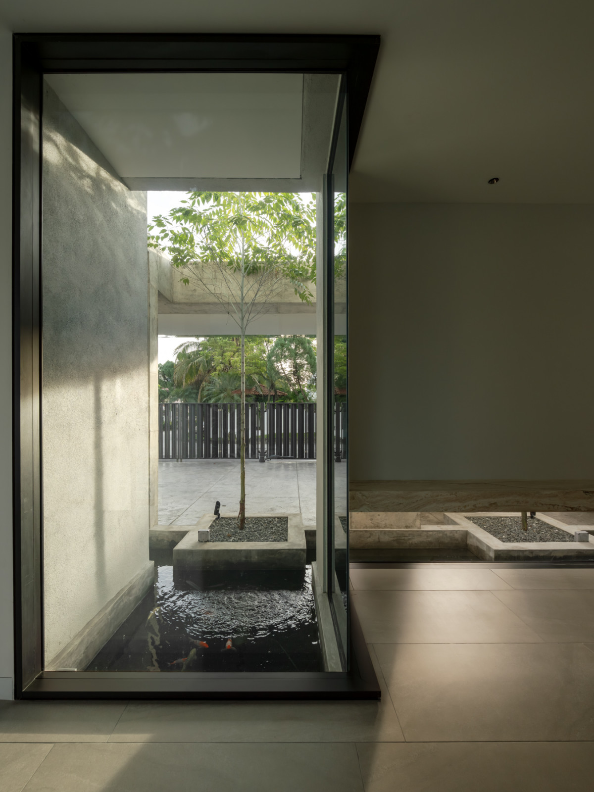 Viewed from inside, glass walls bring the koi pond and courtyard planting into the entrance foyer