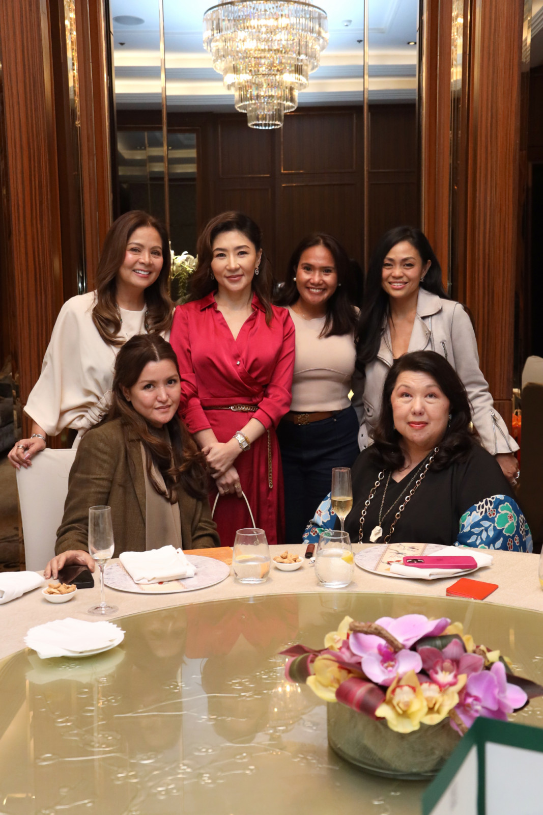 An elegant group of women shares a luxurious luncheon, celebrating refined beauty.
