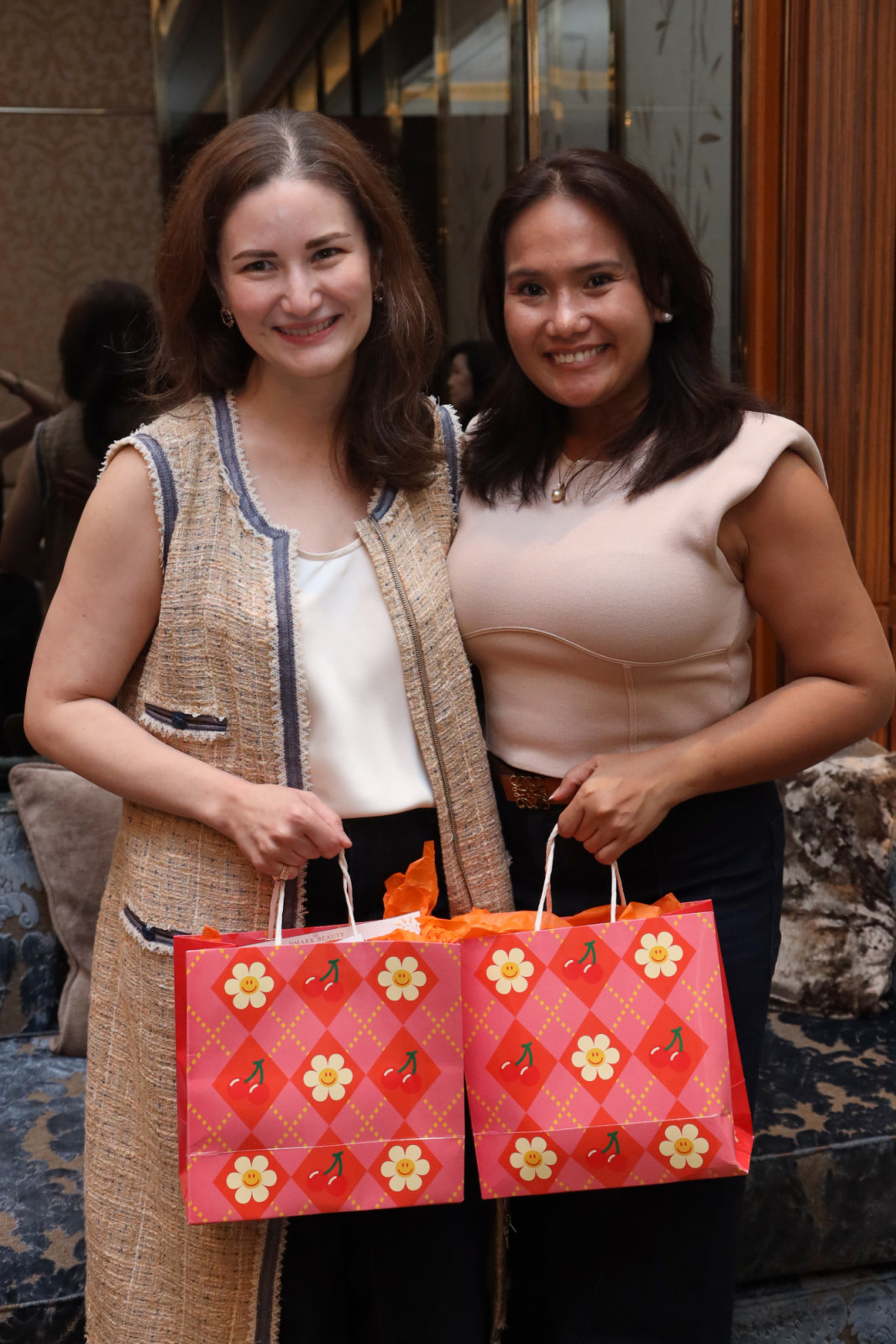 Two women at a beauty event, each holding a Mark Beauty gift bag.