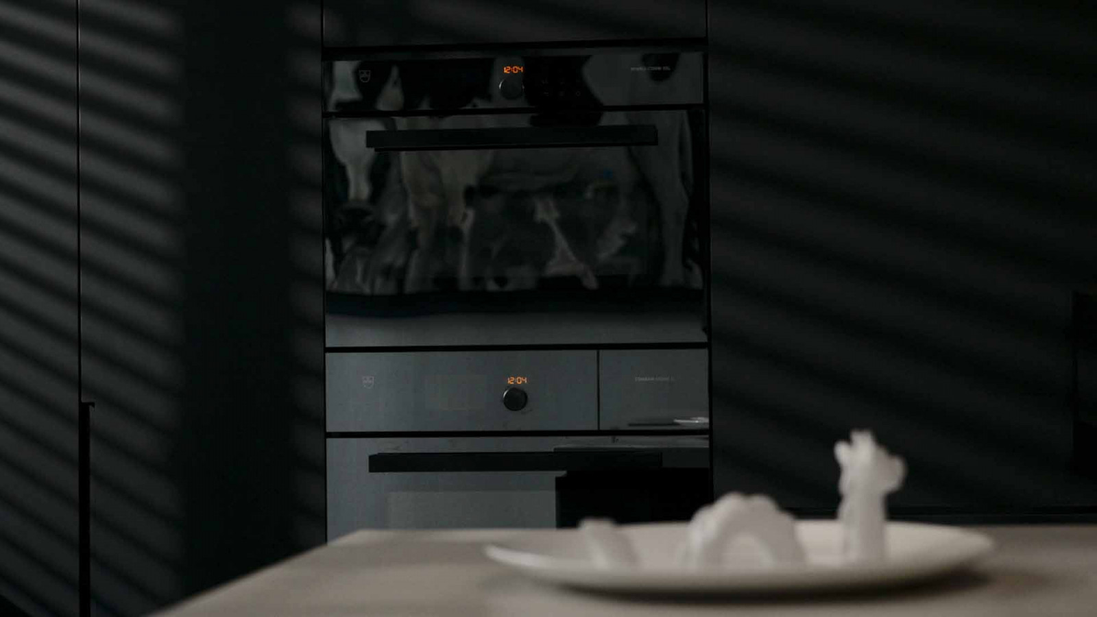A V-ZUG oven glows quietly in the background of the kitchen