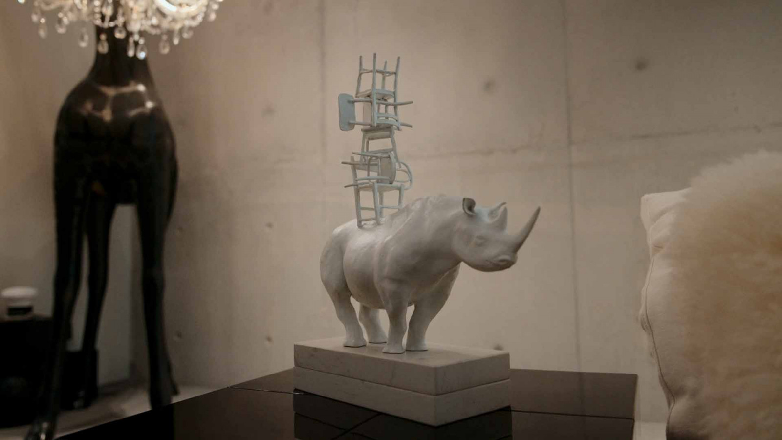 A whimsical rhinoceros sculpture, stacked improbably with a tower of chairs