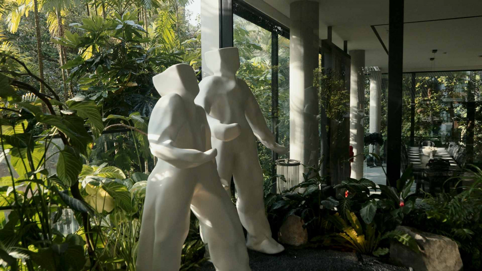 Two of Daisy Boman's life-sized "Bo-men" figures, caught mid-stride against the home's tropical greenery