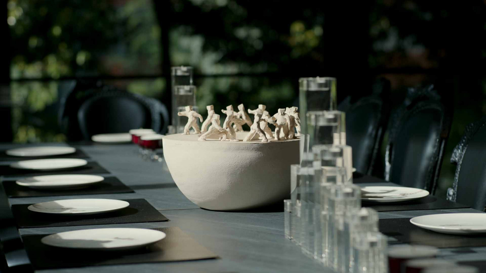 A sculpture comprising a cluster of small figures gathers at the centre of the dining table