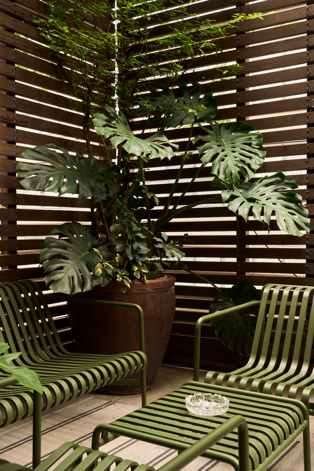 Linear outdoor furniture by Hay echoes the balcony’s panelled walls, the monstera’s green colour perfectly blends with the furniture