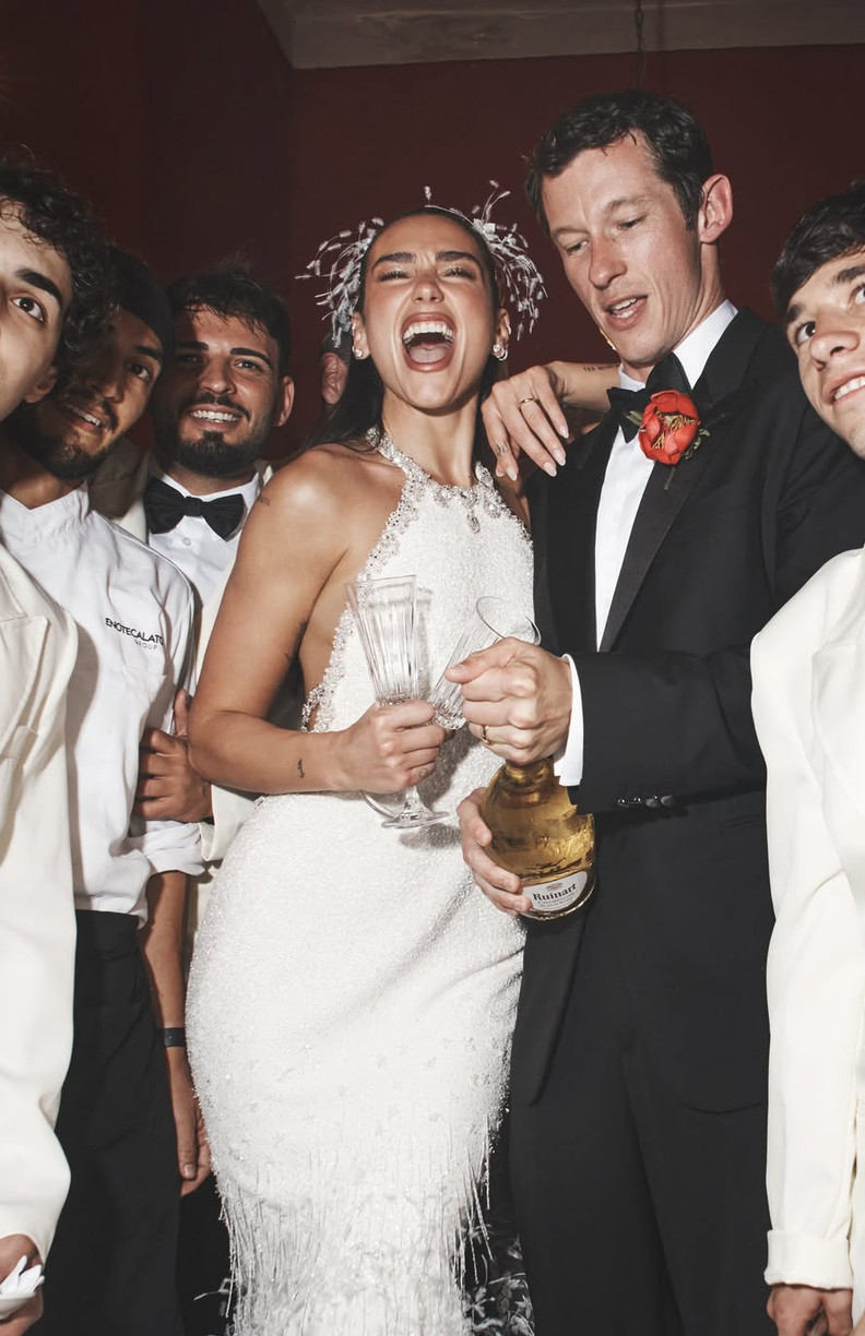 Dua Lipa joyfully celebrates with friends and guests, as one holds a bottle of Ruinart champagne.