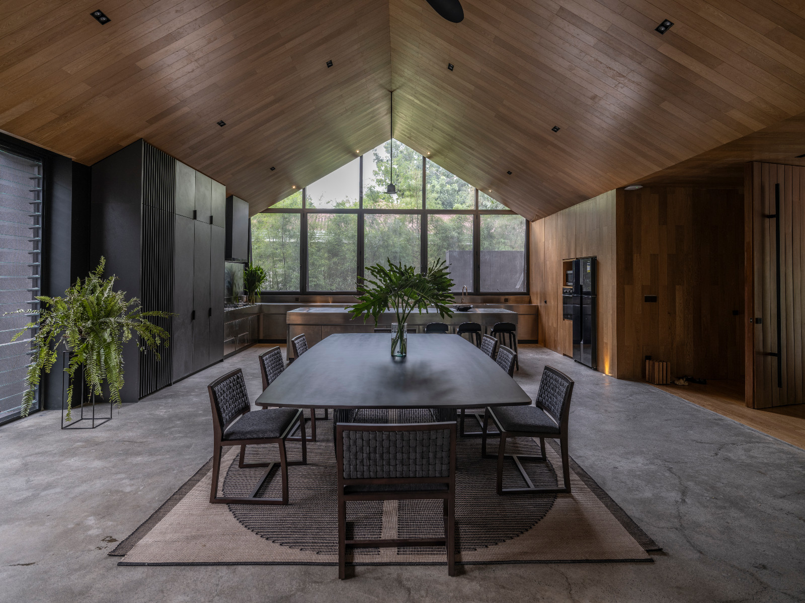 A vaulted timber ceiling and wall of windows create a bright, airy setting for the home’s kitchen and dining space