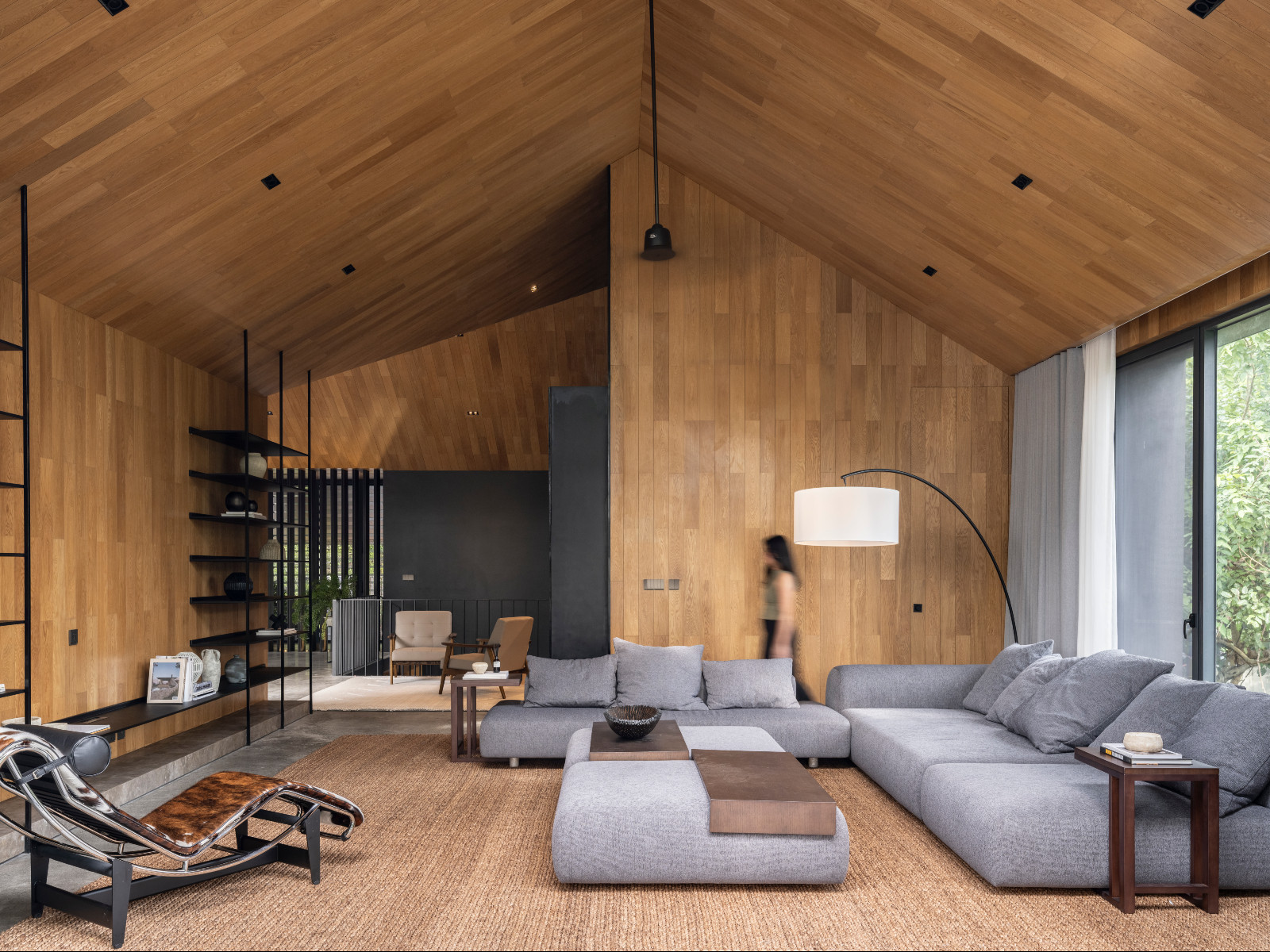 Imagined as a single open space, the double-height living room is anchored by warm timber finishes, expansive glazing, and views of the surrounding trees, reinforcing the Antipolo home’s close connection to its natural setting