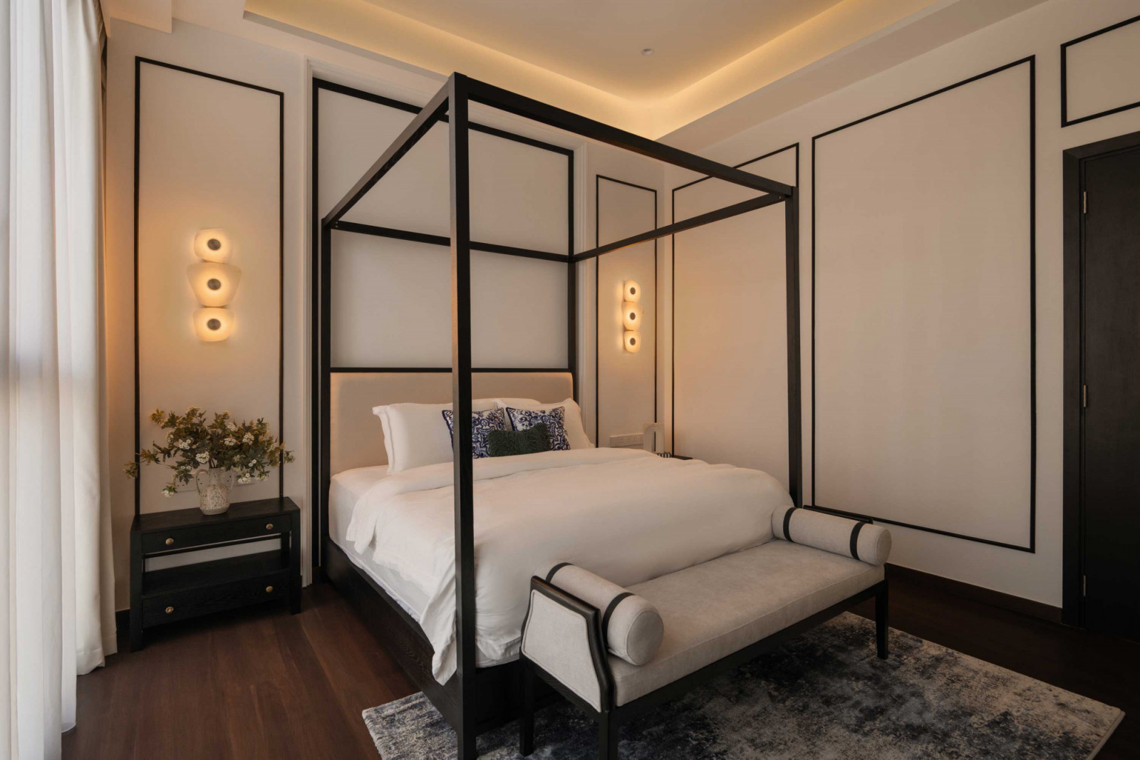 The master bedroom’s four-poster bed emanates a sense of modernity and architectural elegance with its streamlined black-metal frame