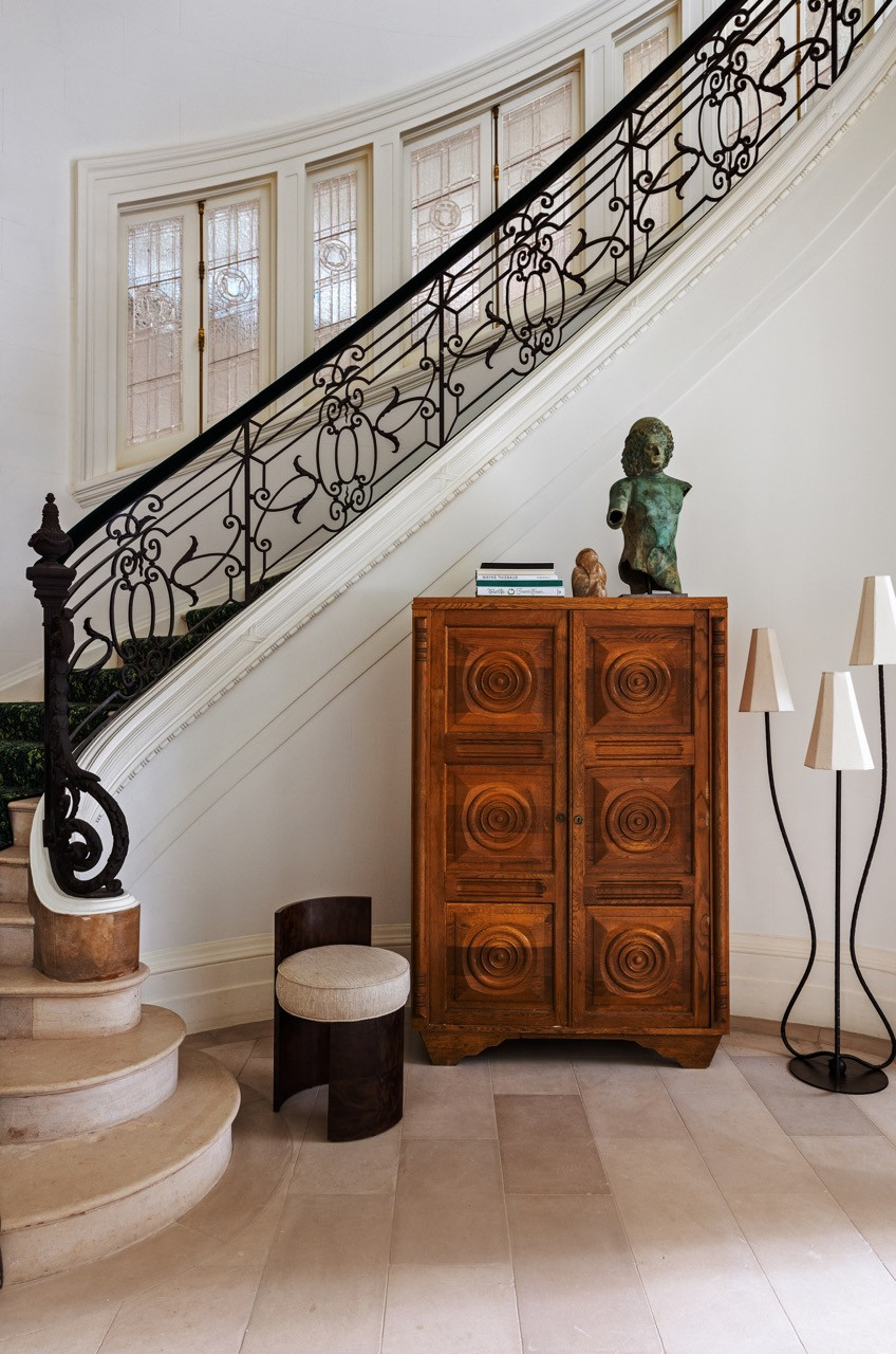 On the staircase landing, a Charles Dudouyt cabinet from Antik Brooklyn is topped with a bronze bust.