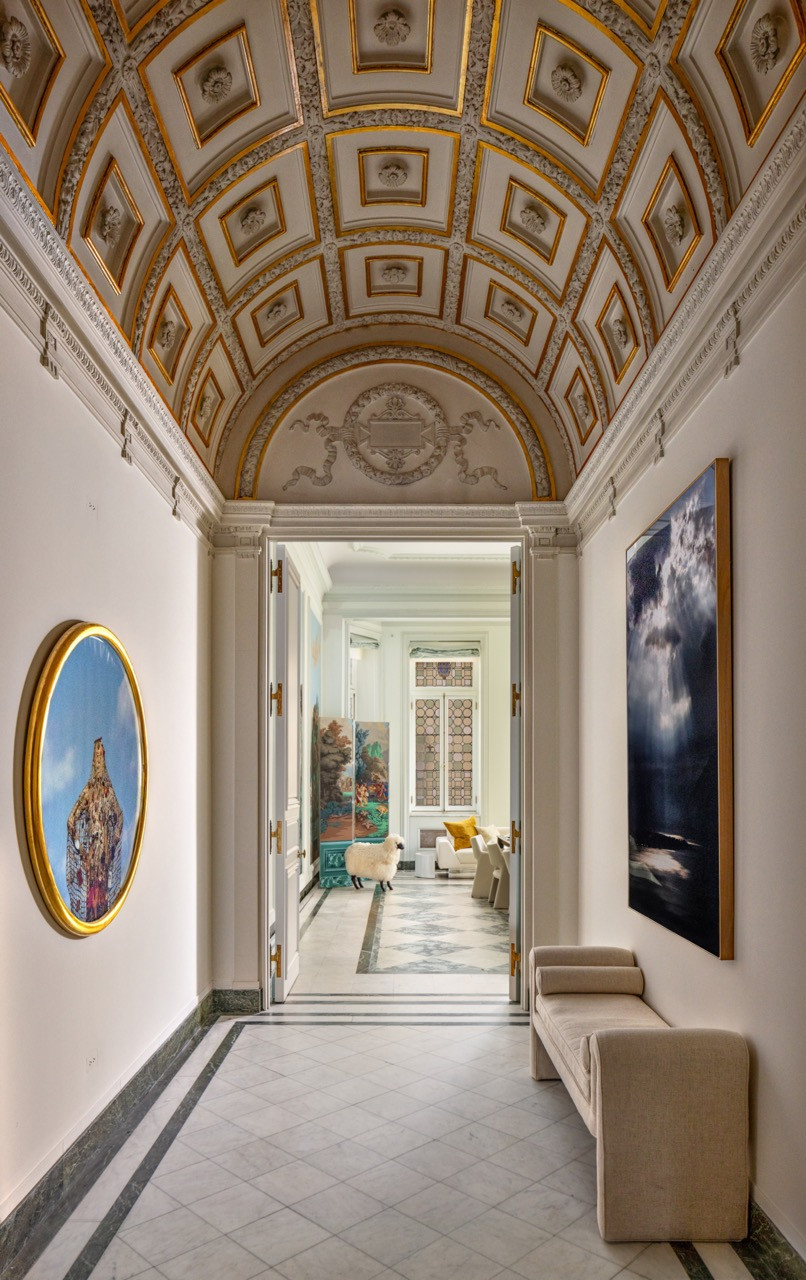 A vaulted, coffered ceiling runs the length of a corridor connecting the mansion’s reception rooms, with a sculptural sheep visible in a sitting room beyond